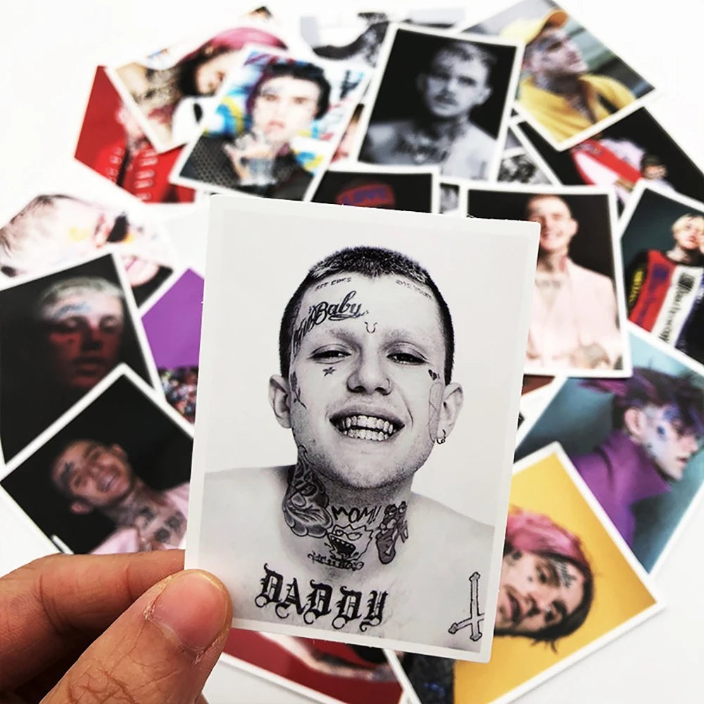 A hand holds a white card featuring a black and white portrait of Lil Peep with tattoos and the word daddy.