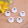 A set of five small white resin coffee cups with black interiors resting on a wooden surface next to a yellow flower.