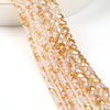 A close-up of a strand of faceted crystal glass beads in a warm amber or peach color.