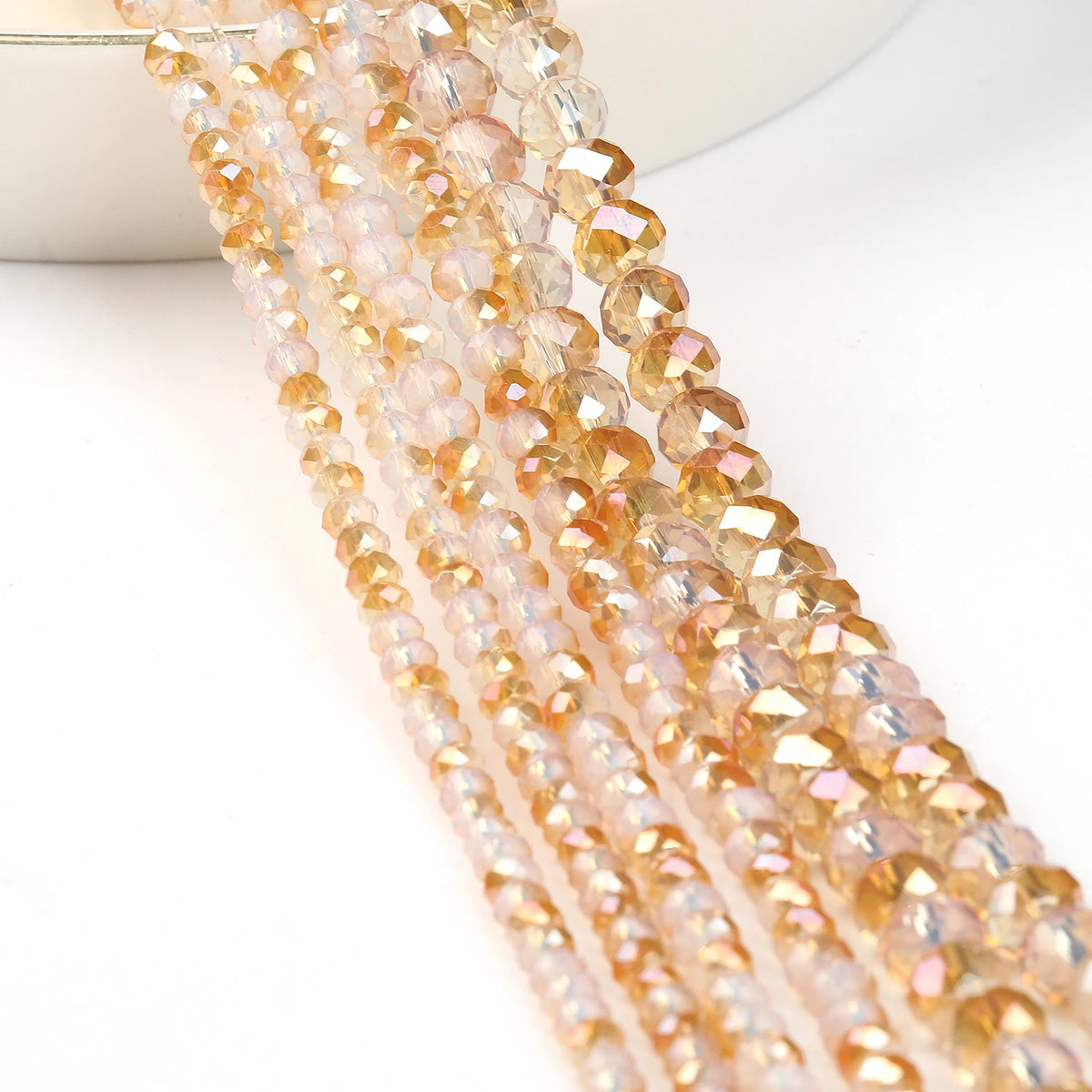 A close-up of a strand of faceted crystal glass beads in a warm amber or peach color.