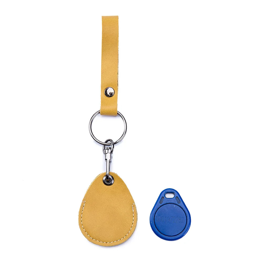 A tan leather key wallet with a hanging loop and a blue tag is shown against a white background.