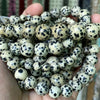 A handful of small, round natural gemstone beads in various colors including tiger eye, lava, and turquoise.