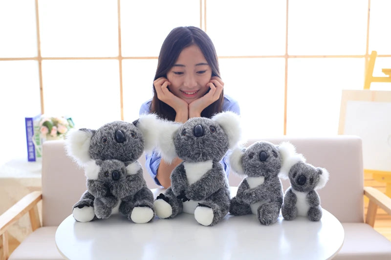 A collection of gray and white koala plush toys sitting on a white surface.