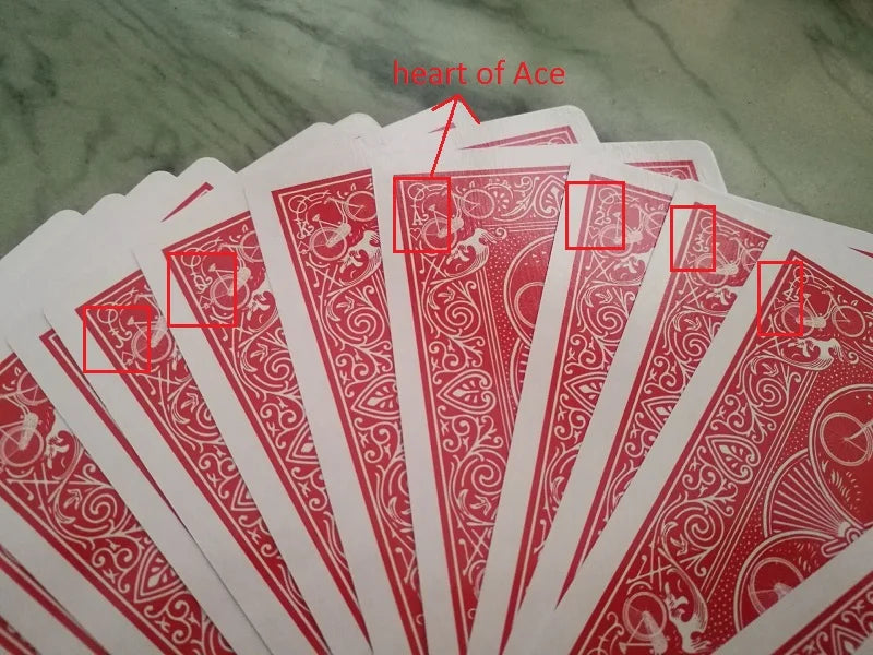 Close-up view of a deck of playing cards with red decorative patterns and marked areas labeled as the heart of Ace.