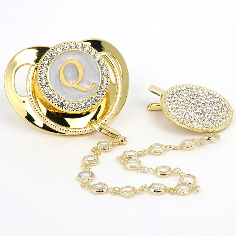 Gold and clear rhinestone pacifier featuring a personalized initial on a silicone clip.