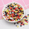 A bowl filled with colorful cartoon polymer clay slices in various colors like red, yellow, black, and white for crafting.