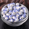 A clear glass bowl filled with small white and blue floral ceramic beads for jewelry making