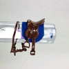 A brown leather horse saddle and riding prop accessory placed on a clear plastic display bar.
