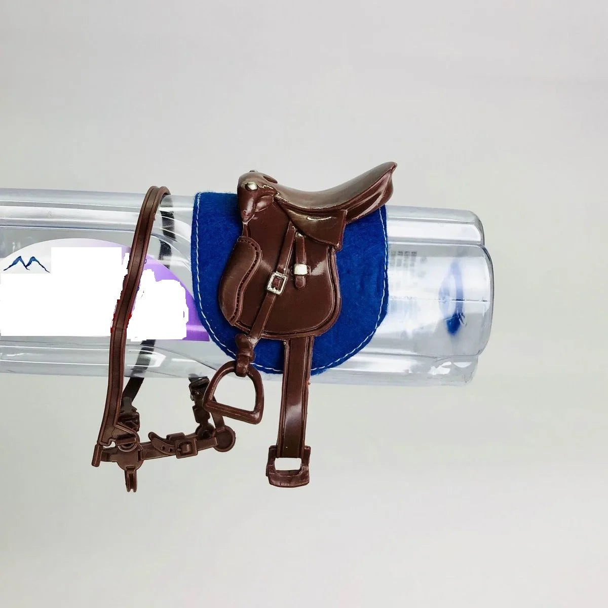 A brown leather horse saddle and riding prop accessory placed on a clear plastic display bar.