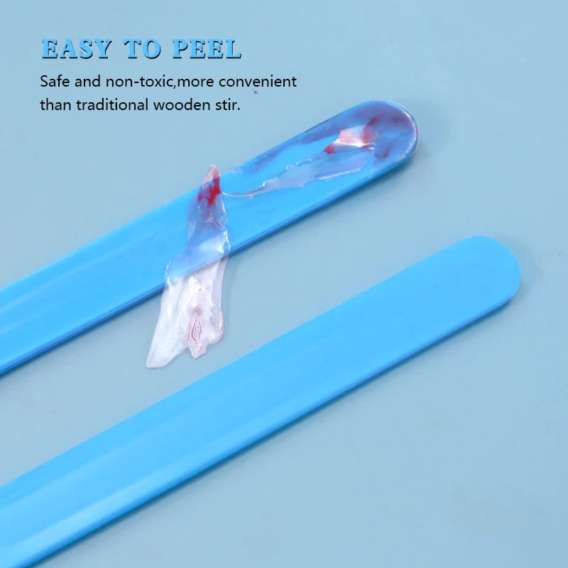 A blue silicone resin mixing tool kit showing a stir stick with a small amount of red liquid on a light blue background.