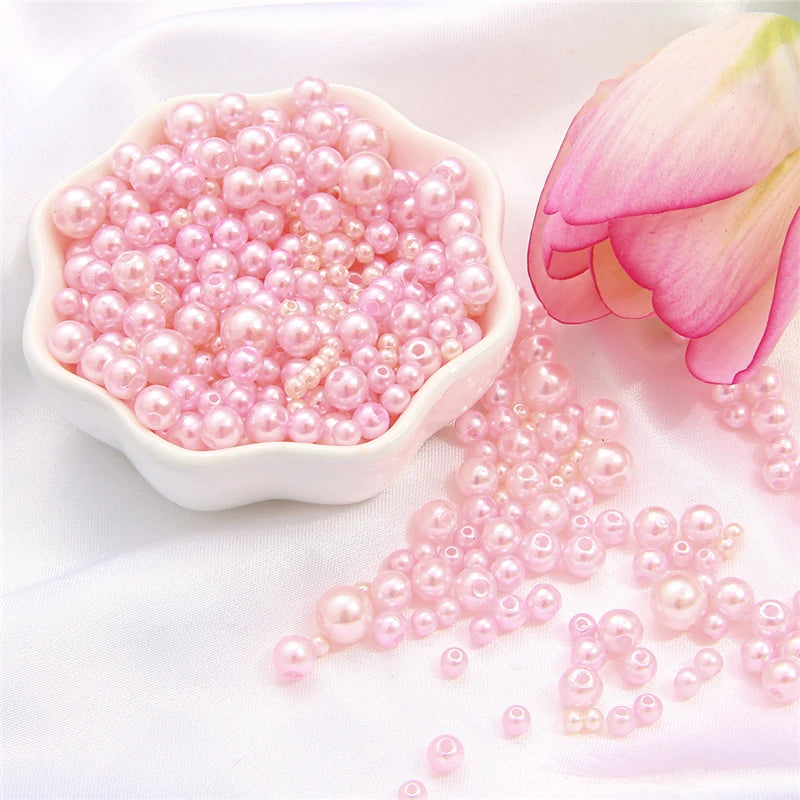 A pile of assorted pink and white pearl beads for jewelry making next to a light pink lotus flower.