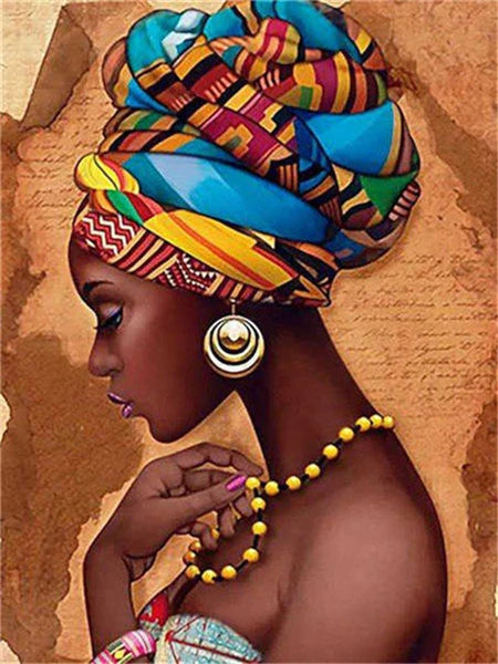 A close-up portrait of a woman with vibrant patterned headwrap and gold earrings, holding a painting tool.