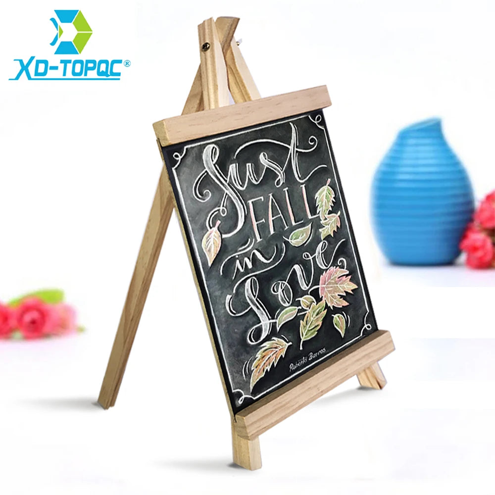 A mini wooden chalkboard easel displaying the phrase Just Fall in Love with decorative leaves.