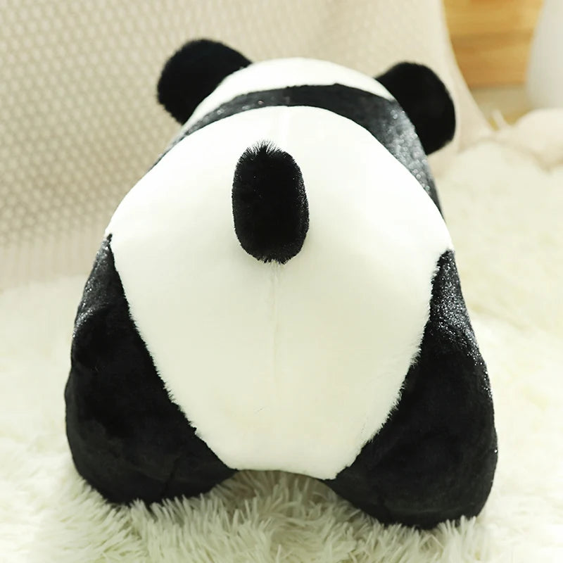 A black and white panda plush toy with soft fur resting on a white fluffy surface.