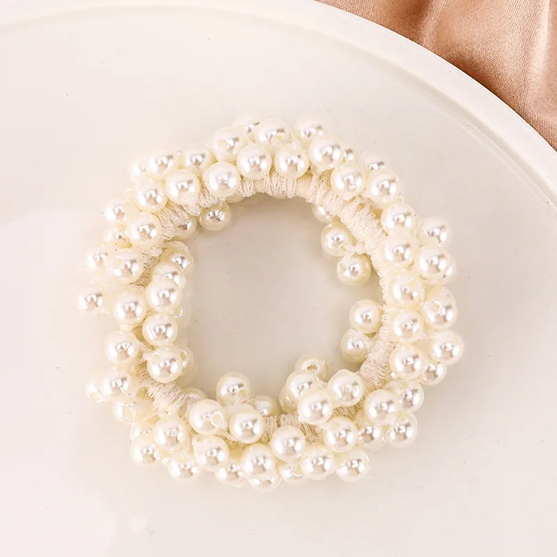 A close-up of elegant pearl hair ties arranged in a wreath shape on a white plate.