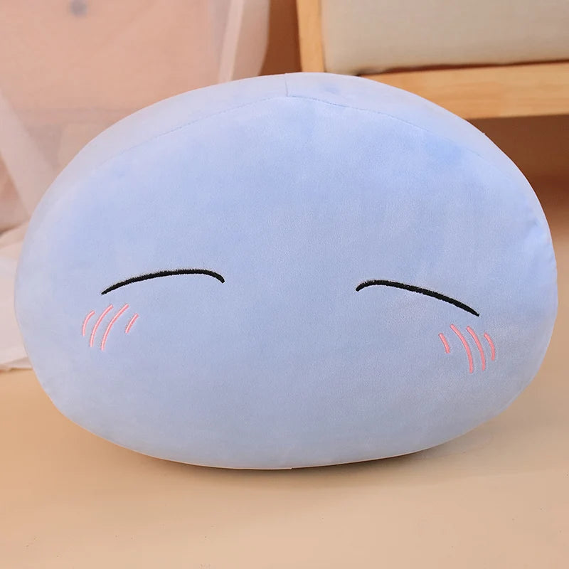 A light blue plush toy pillow shaped like a face with closed eyes and rosy cheeks.