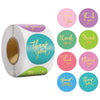 Roll of colorful round thank you stickers in various shades of pink, green, and yellow.