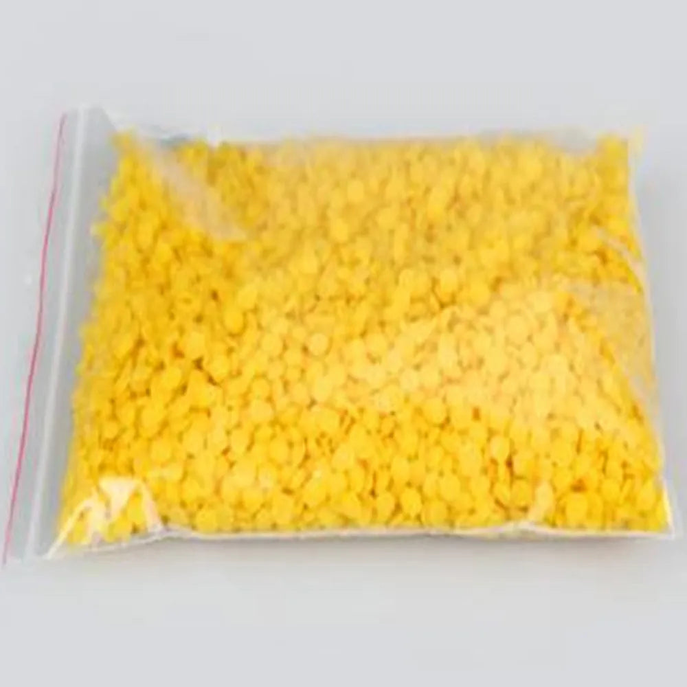 A clear plastic bag filled with bright yellow natural beeswax pellets for DIY candle making and skincare.