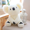 A white koala plush toy with black accents sitting next to a glass-like decorative object.