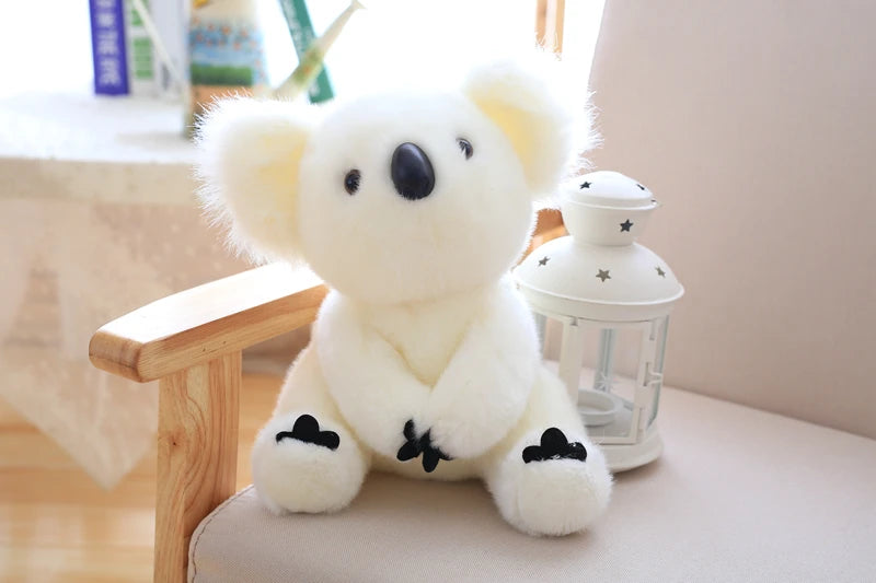 A white koala plush toy with black accents sitting next to a glass-like decorative object.