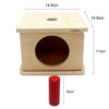 A wooden sensory toy set featuring a box with a circular opening and a separate red cylinder.
