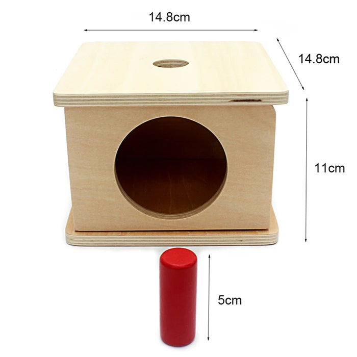 A wooden sensory toy set featuring a box with a circular opening and a separate red cylinder.
