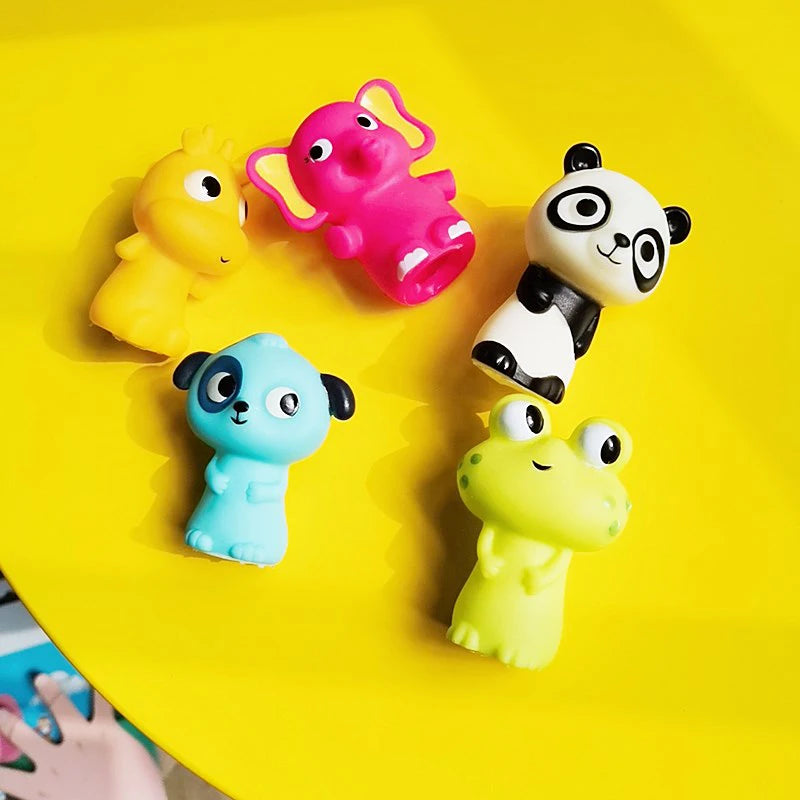 A collection of colorful animal finger puppets including an elephant, panda, blue creature, and yellow frog on a bright yello
