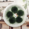 A white plate holds several dark green mink fur pom poms for crafts and accessories.