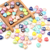 A collection of multicolor heart-shaped acrylic beads in various shades are displayed on a wooden tray.