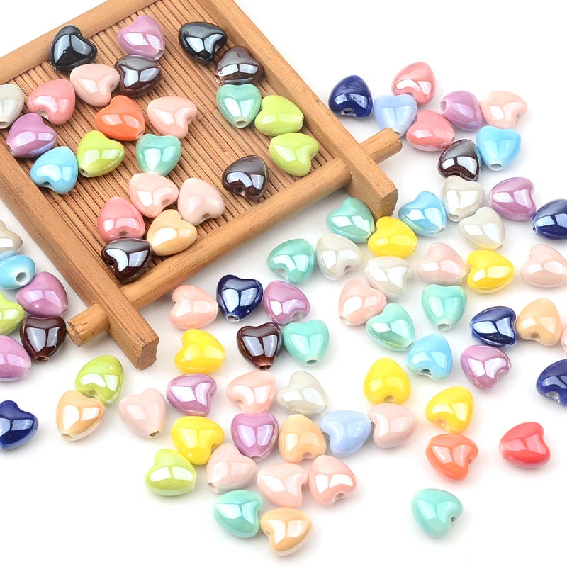 A collection of multicolor heart-shaped acrylic beads in various shades are displayed on a wooden tray.