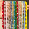 A collection of colorful faceted crystal glass beads in various shades of pink, blue, green, and yellow strung together for j