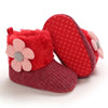 A pair of red plush baby snow boots with pink floral accents and anti-slip soles.