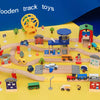 A set of wooden train track toys featuring various scenes like an airport and gas station with different vehicles and structu