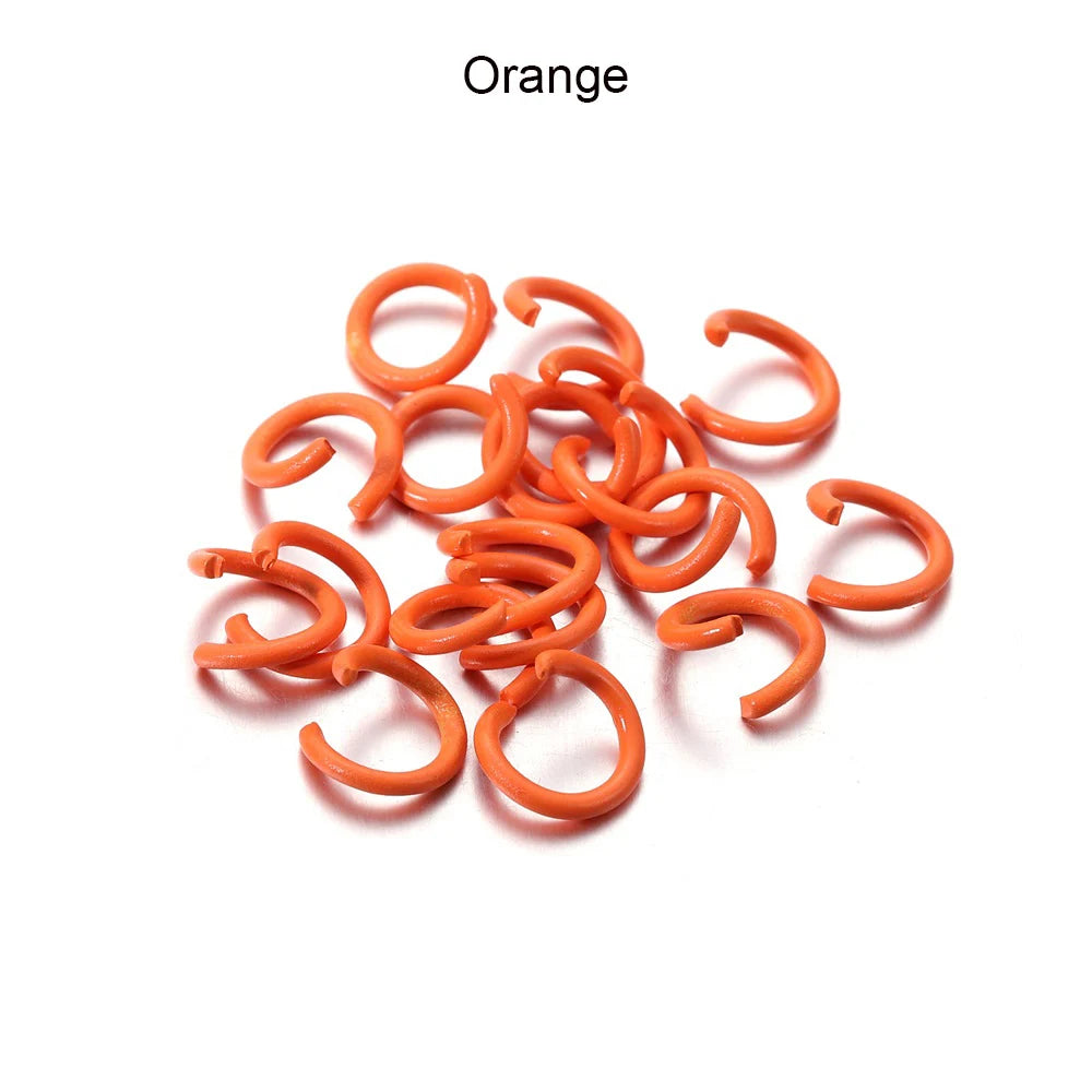 A pile of orange metal open jump rings for DIY jewelry making.