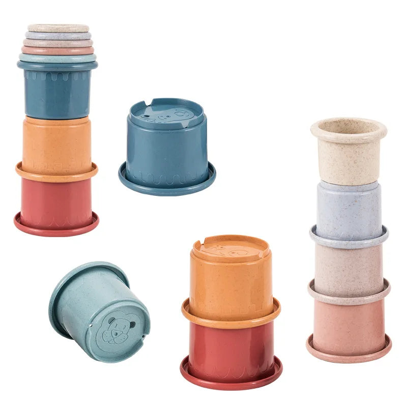 A set of boat-shaped stacking cups in various shades of blue, orange, and pink for toddlers.