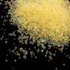 A pile of small, translucent yellow glass bubble beads scattered against a black background.