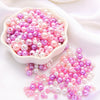 A pile of assorted pink and purple pearl beads for jewelry making displayed in a white dish.