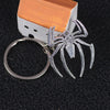 Silver spider pendant charm attached to a rectangular white and orange box keychain.