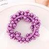 A circular hair accessory made of purple pearls and pink thread, resembling a bow scrunchie.