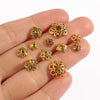 A hand holds several gold-colored Tibetan style hollow flower bead caps for jewelry making.