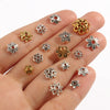 A hand displays various Tibetan style hollow flower bead caps for jewelry making in silver and gold tones.