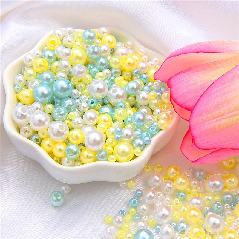 A bowl filled with assorted pale yellow and blue pearl beads next to a pink lotus flower.