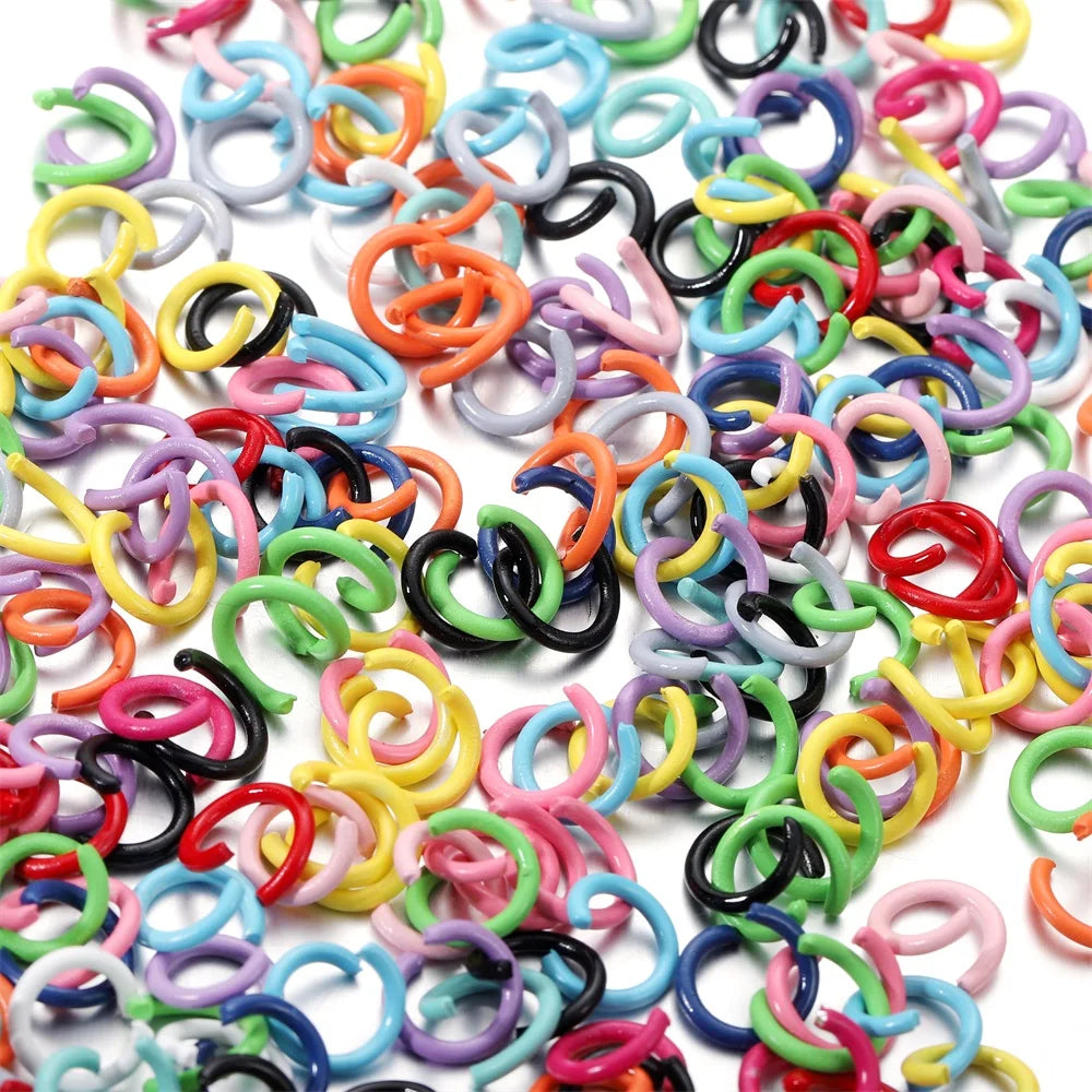 A pile of colorful metal open jump rings in various shades including pink, blue, yellow, and black.