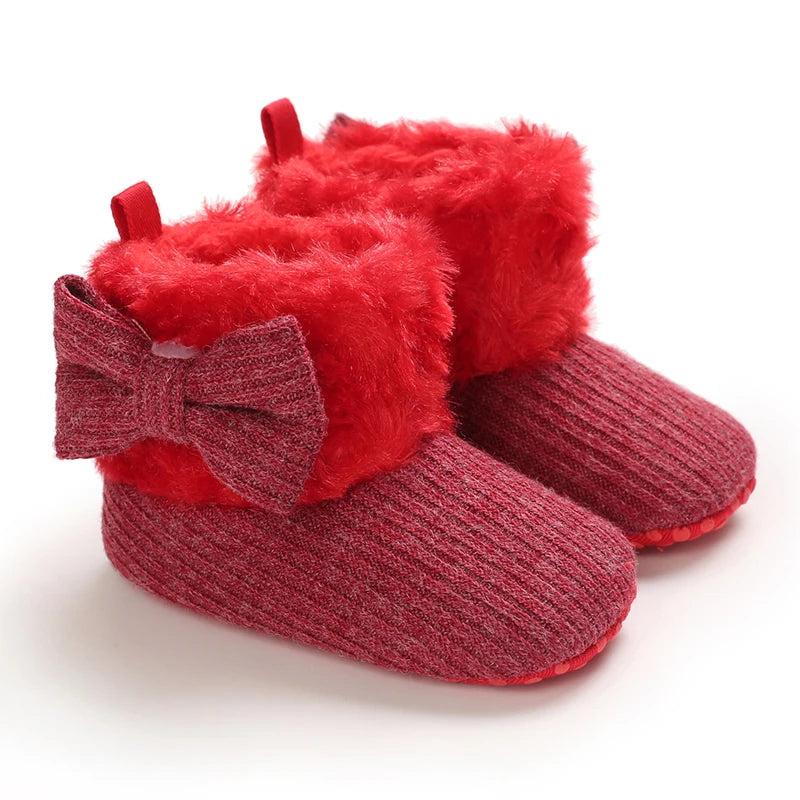 Pair of red plush baby snow boots with fluffy red trim and anti-slip soles