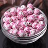 A bowl filled with pink and white floral ceramic beads for jewelry making