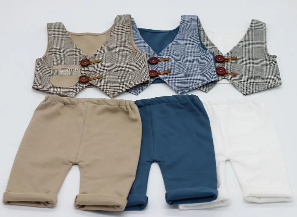 A set of newborn photography outfits featuring plaid vests and matching beige, navy blue, and white bottoms.