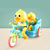 A yellow duck toy is seated in a blue electric tricycle with a green frame.
