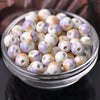 A bowl filled with small ceramic beads in shades of white and purple floral patterns for jewelry making