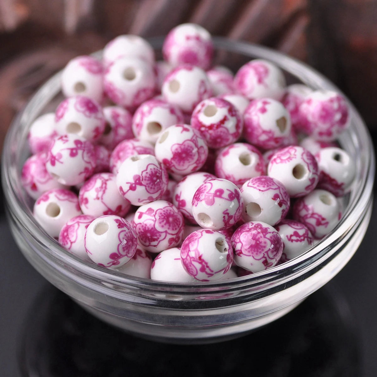 A bowl filled with small pink and white floral ceramic beads for jewelry making