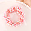 Pink pearl hair ties with a delicate pink cord arranged in a circular wreath shape.